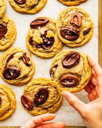 hand picking up rye chooclate chip cookie from a tray