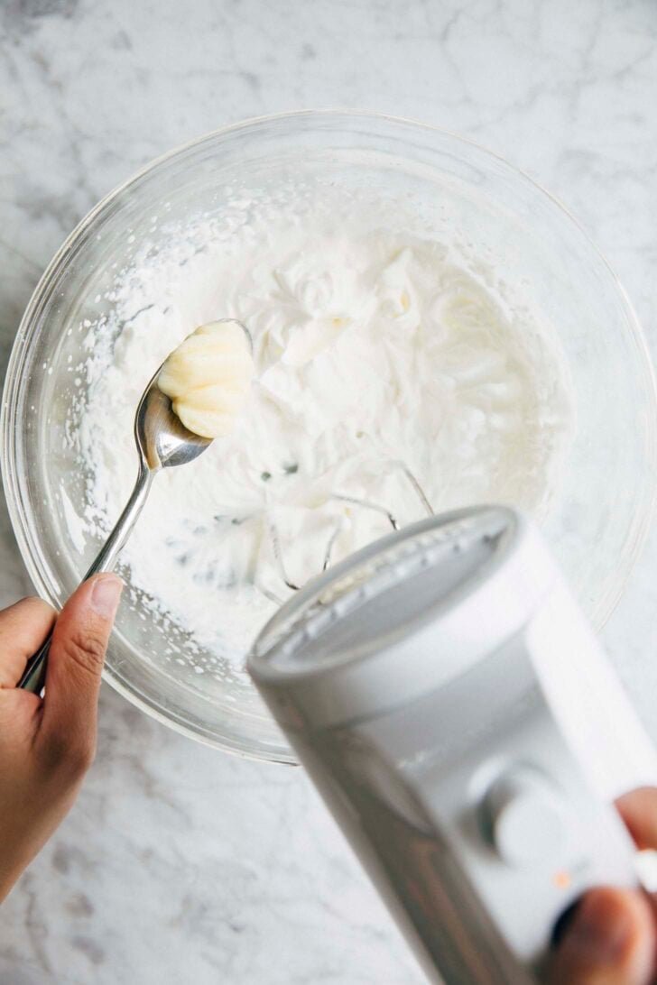 Photo of Michelle from Hummingbird High adding spoonfuls of the pudding mix base to the whipped cream