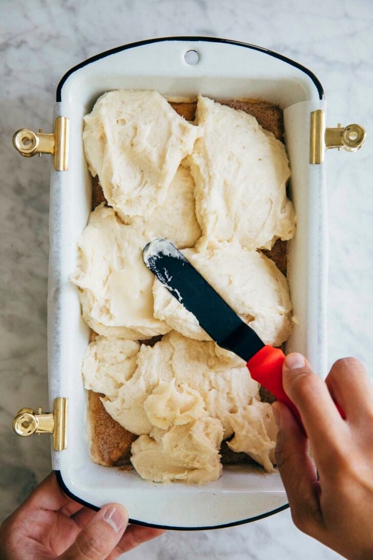 photo showing process of making snickerdoodle bread: michelle of hummingbird high putting the remaining batter on top of the snickerdoodle swirl