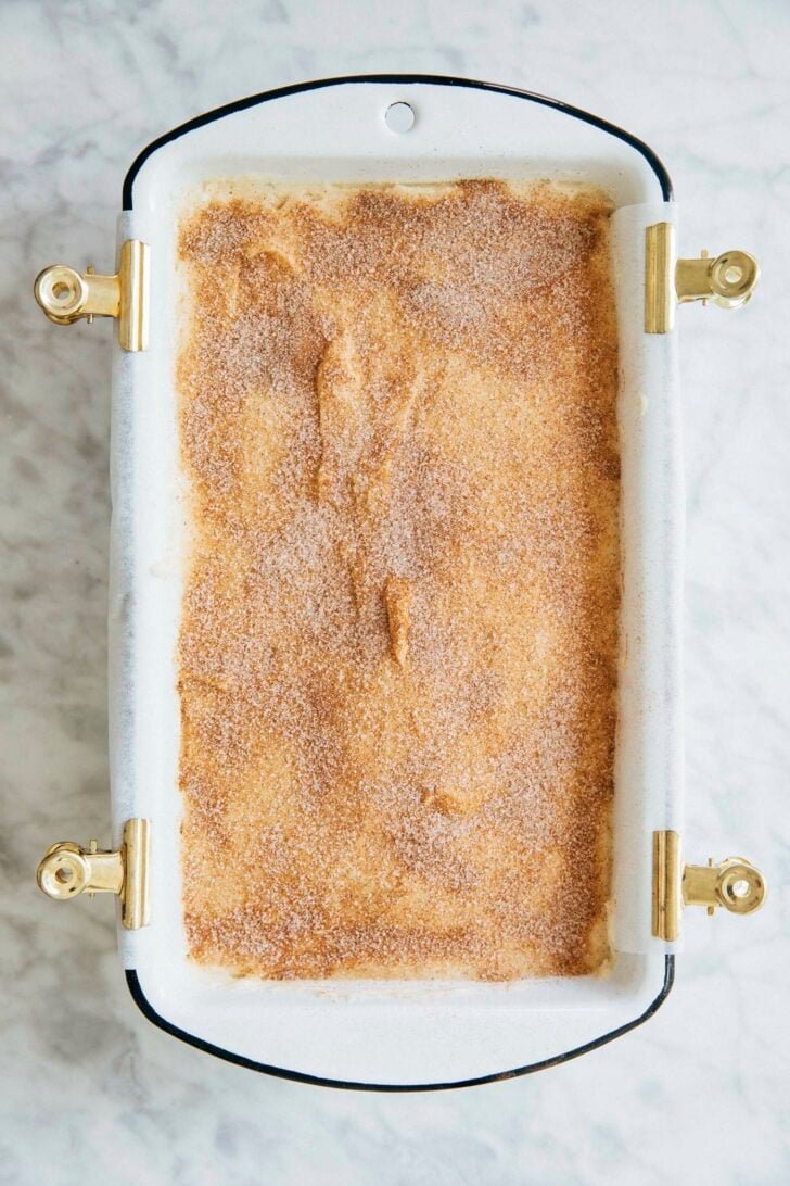 photo showing process of making snickerdoodle bread: final layer of cinnamon sugar topping on top of the cake batter before it's baked