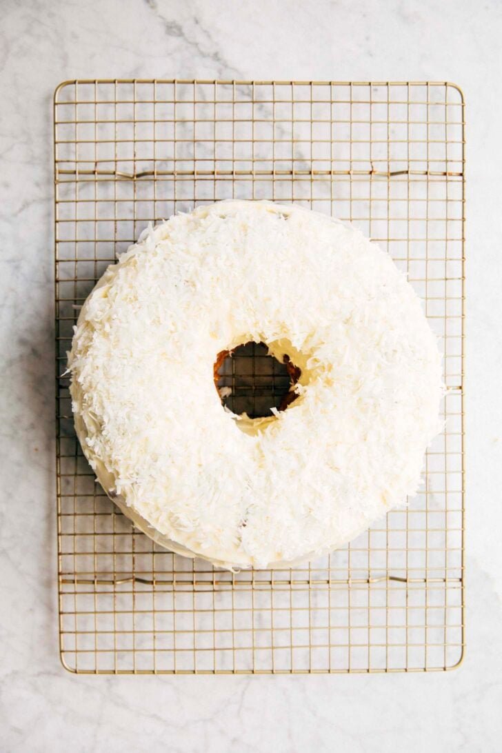 photo of the frosted bundt cake being covered with toasted shredded coconut