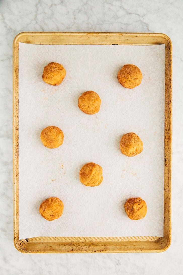photo of snickerdoodle cookie dough balls arranged in hopscotch formation on a baking pan for baking