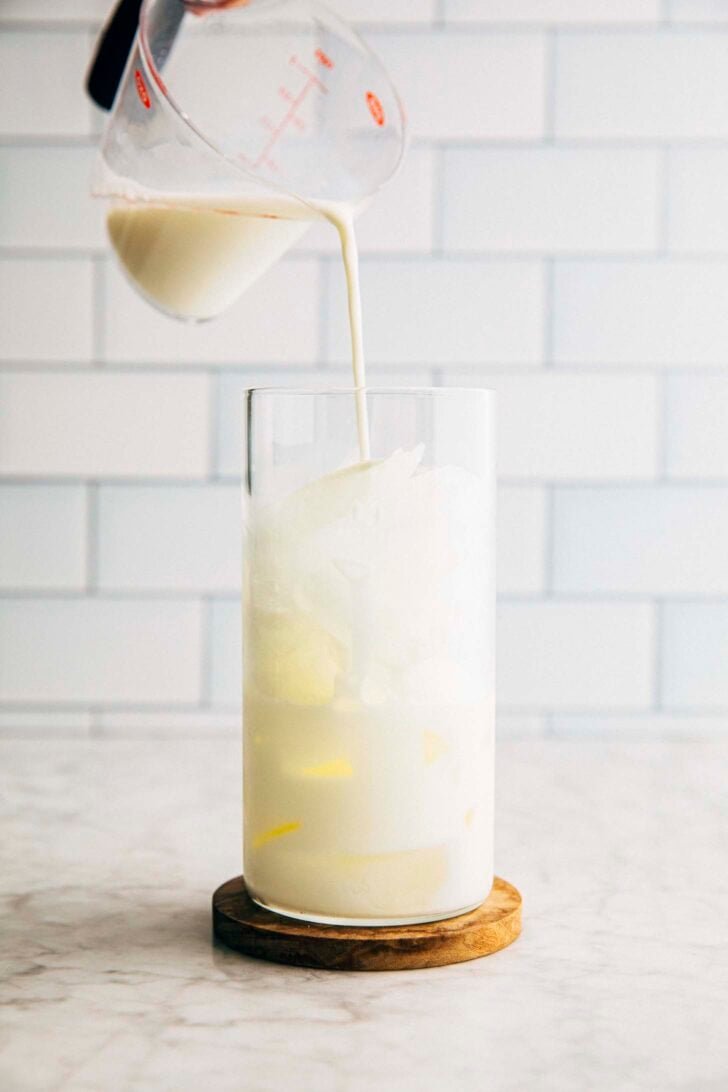 photo of michelle from hummingbird high pouring milk into a tall glass for the matcha einspanner