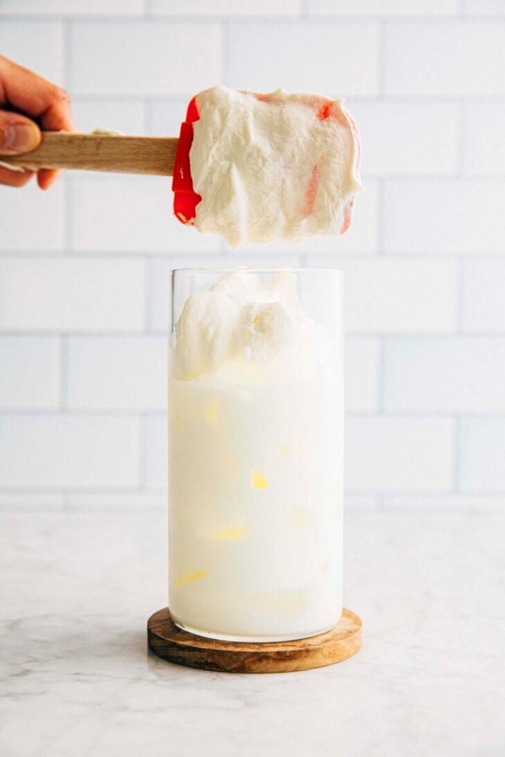 photo of michelle from hummingbird high scooping the first scoop of einspanner cream into the latte