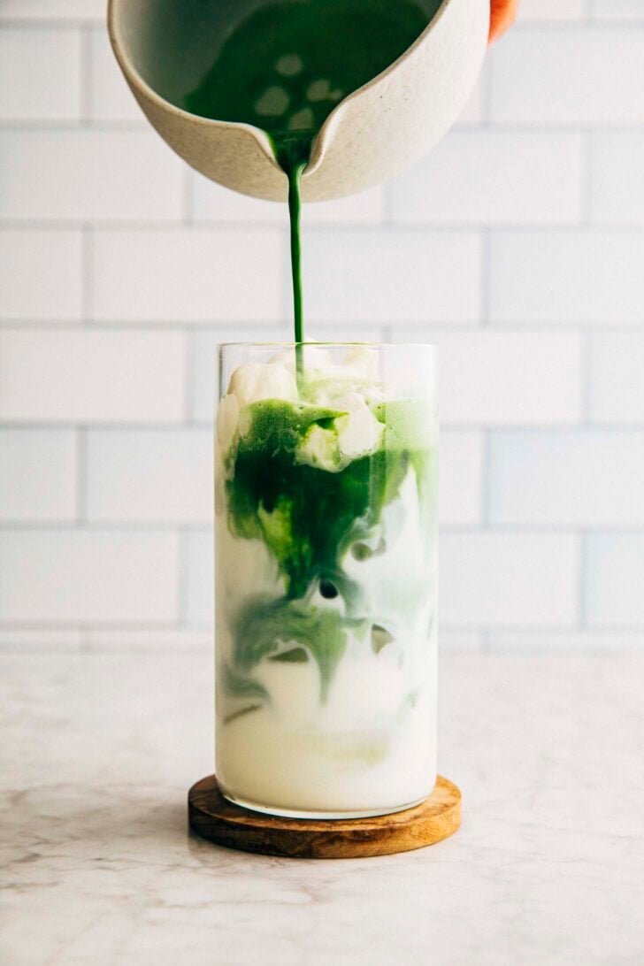 photo of michelle from hummingbird high pouring the matcha over the einspanner cream into the latte