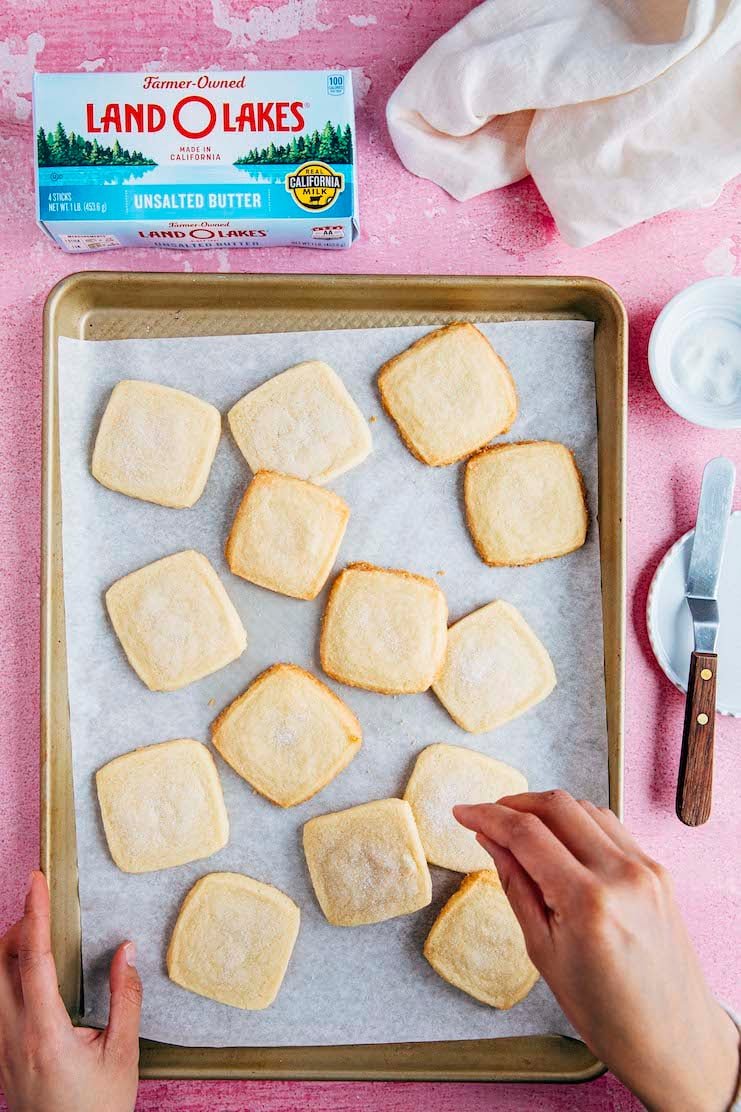 hand sprinkling sugar over shortbread cookies