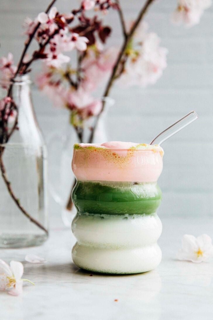 photo of cherry blossom matcha in a wavy glass next to vases with cherry blossoms