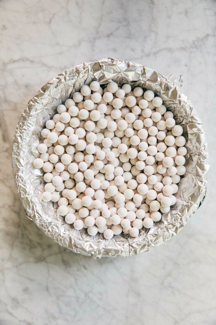 photo showing the pie crust before pre baking wrapped in foil and weighed down with pie weights