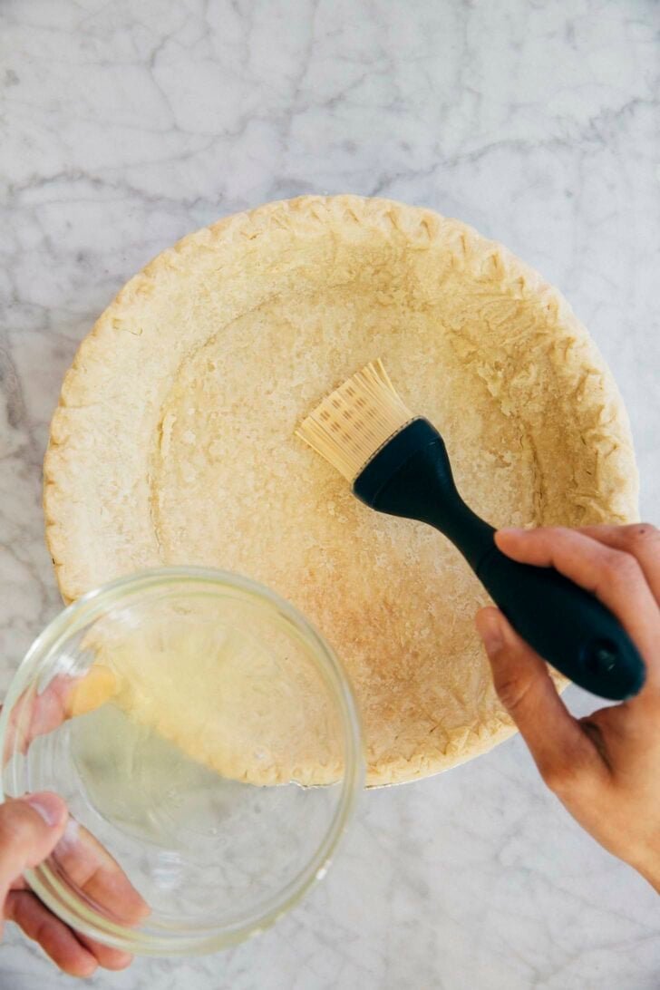 photo showing michelle of hummingbird high brushing the pre baked pie crust with egg wash