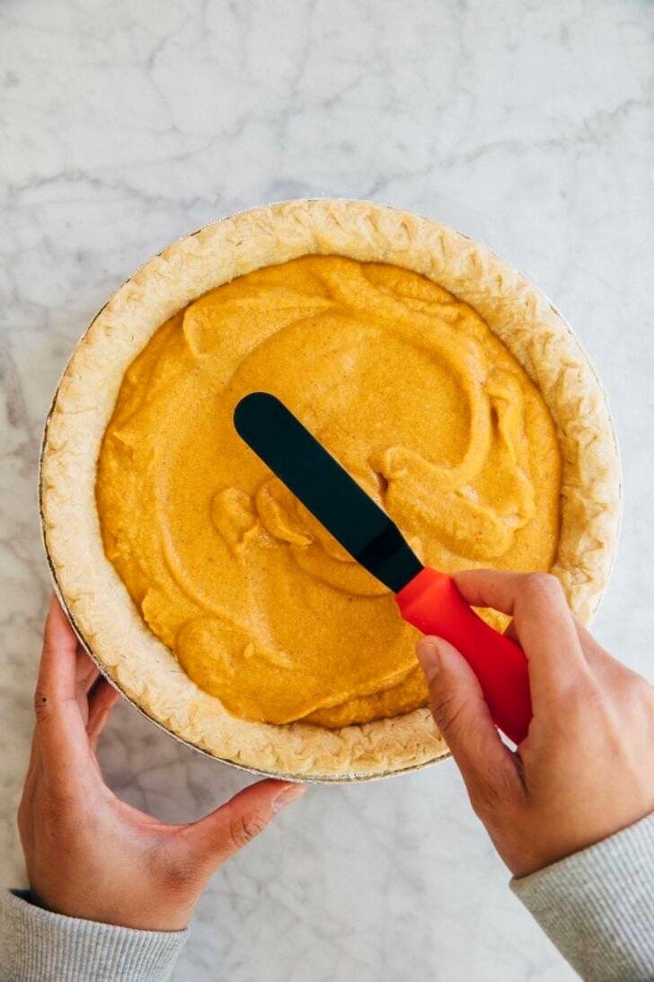 photo of michelle from hummingbird high using an offset spatula to smooth the cream cheese pumpkin pie filling
