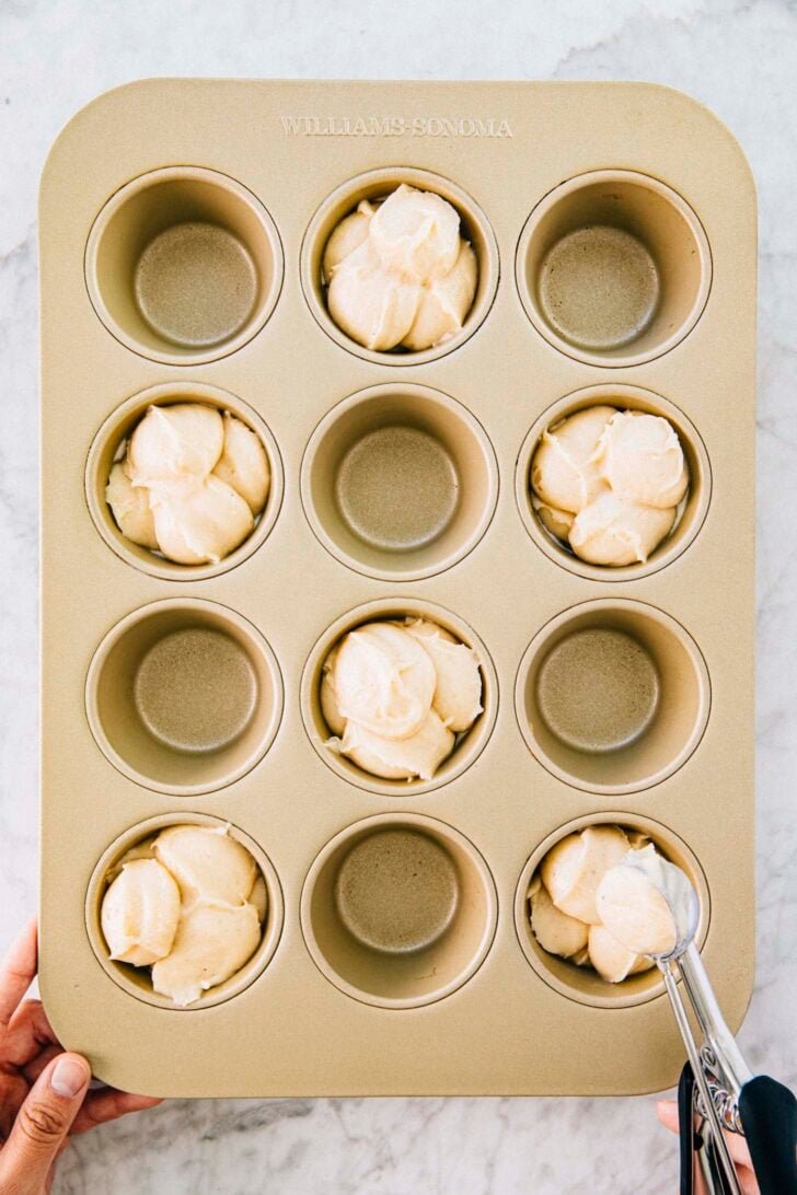 photo of michelle from hummingbird high scooping the snickerdoodle muffin batter into a pan in a hopscotch formation