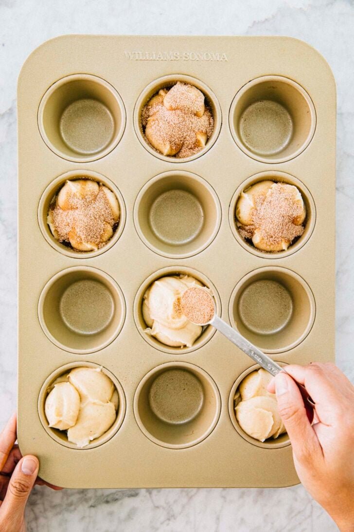photo of michelle from hummingbird high spooning cinnamon sugar over the portioned muffins before baking
