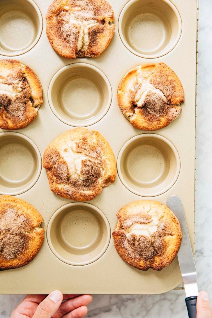 photo of michelle from hummingbird high using an offset spatula to unstick the muffin tops from the pan