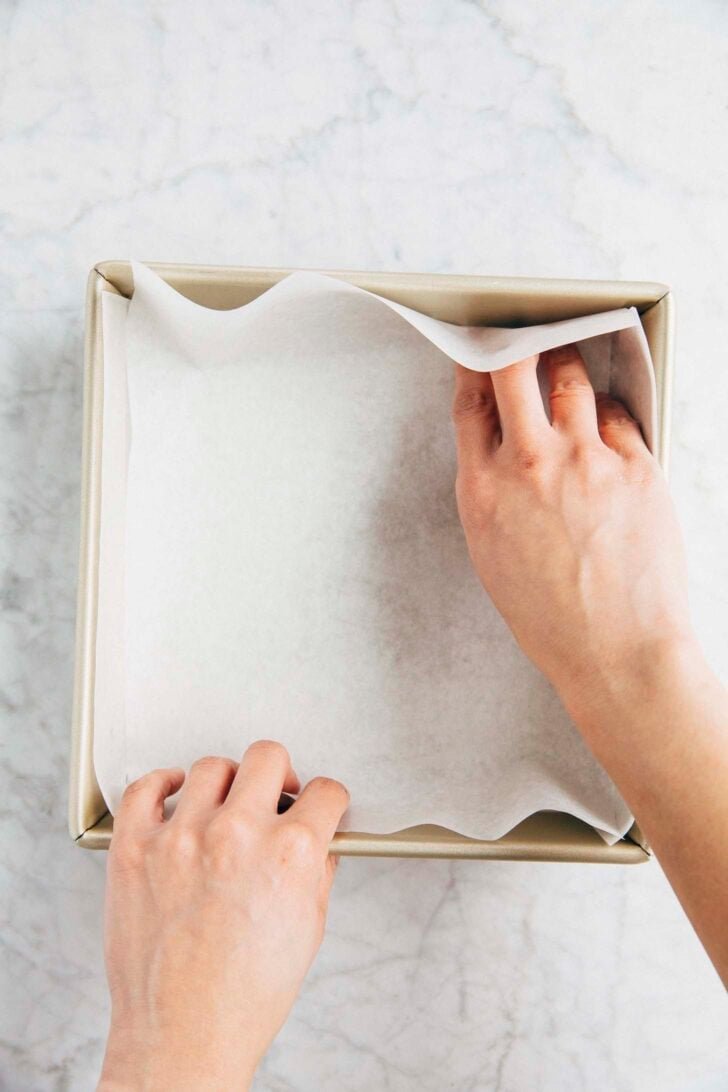 Photo of Michelle from Hummingbird High lining an 8-inch square pan with parchment paper