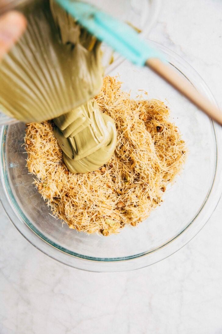 Photo showing the pistachio cream being poured over the cooked kataifi