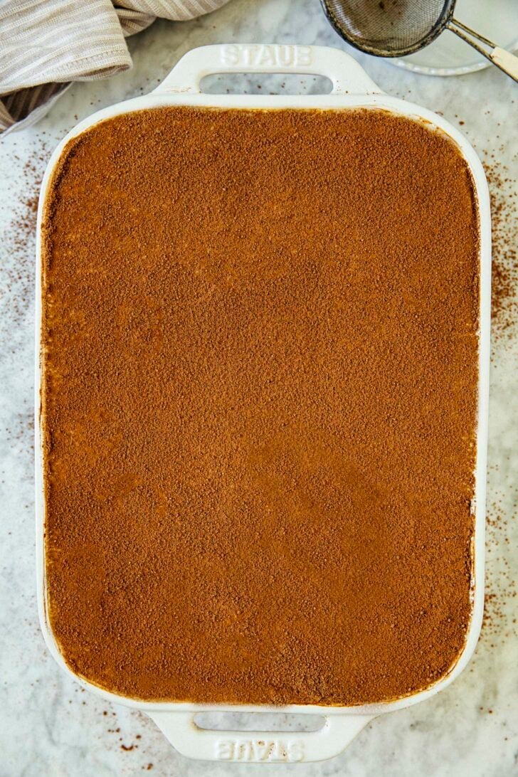 photo of classic tiramisu on marble back drop in a white pan