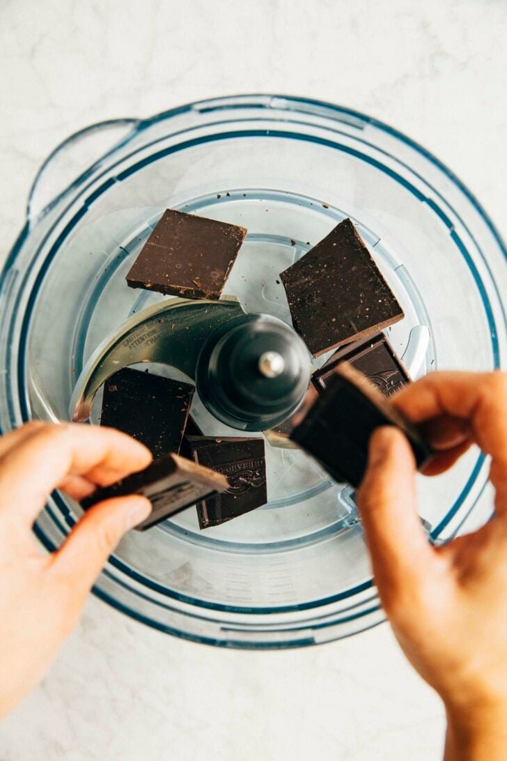photo of michelle from hummingbird high breaking chocolate into a food processor to make chocolate fudge frosting