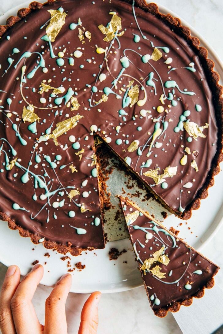 Photo of the Dubai chocolate pistachio tart on a white plate with a slice being served