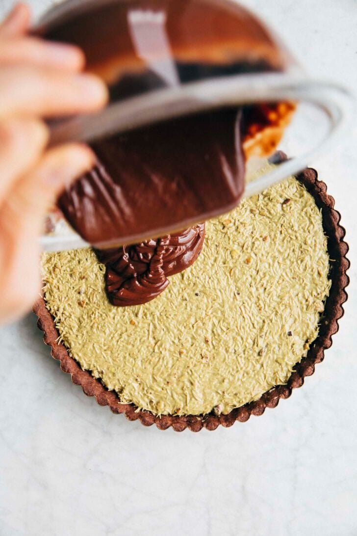 Photo of Michelle from Hummingbird High pouring ganache over the kataifi filling to finish the Dubai chocolate pistachio tart