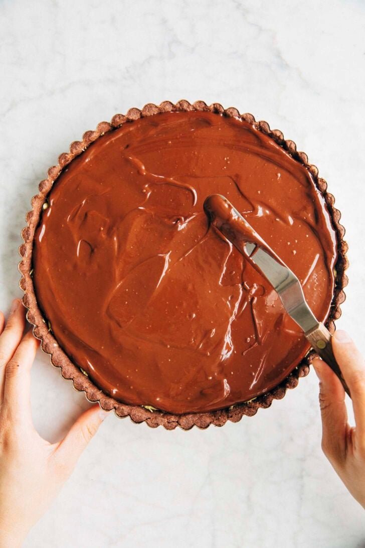 Photo of Michelle from Hummingbird High spreading ganache evenly over the kataifi filling of the Dubai chocolate pistachio tart