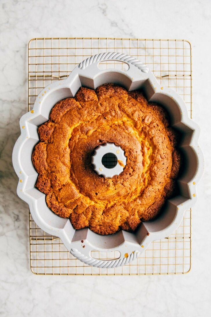 photo of the banana pudding bundt cake after it's been made, still in the bundt pan on a wire rack