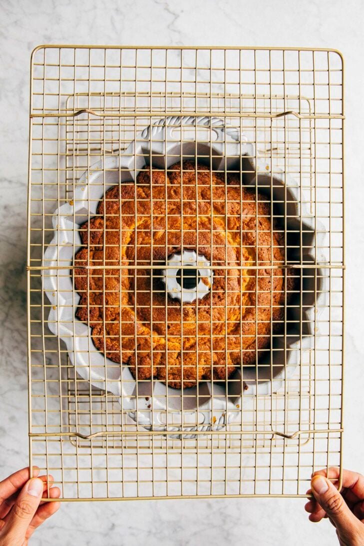 photo of michelle from hummingbird high placing a second wire rack over the bundt cake on a wire rack and preparing to flip the cake to turn it out of its pan