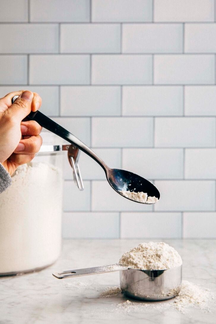 Photo of Michelle from Hummingbird High using a black spoon to scoop flour into a measuring cup
