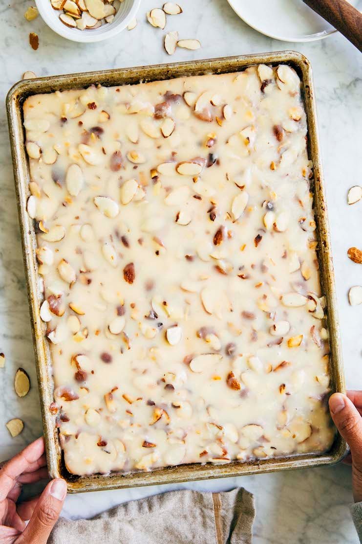 photo of michelle from hummingbirdhigh setting down a white texas sheet cake unsliced in its 9 x 13 inch pan