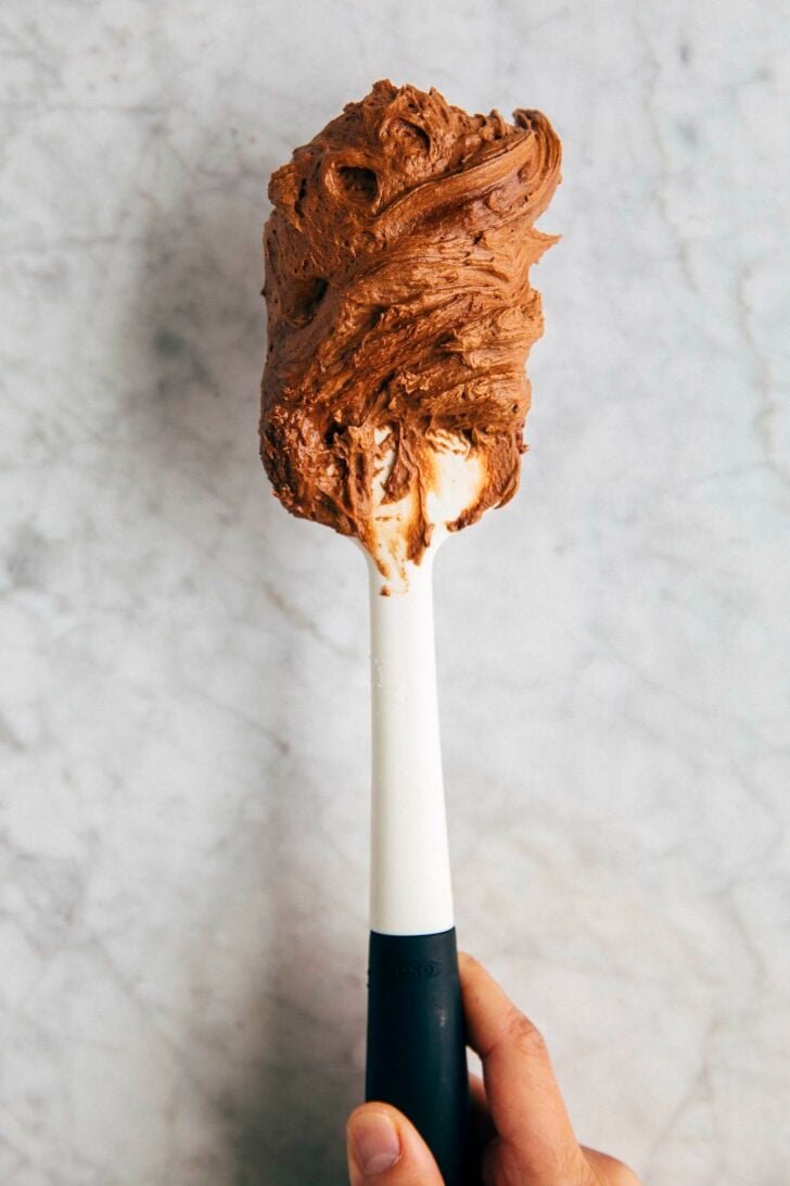 photo of michelle from hummingbird high holding up a spatula with chocolate cream cheese frosting
