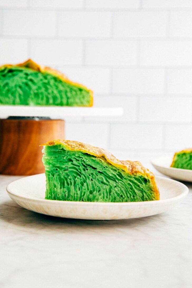 photo of vietnamese honeycomb cake slice in front of a cake stand with the cake