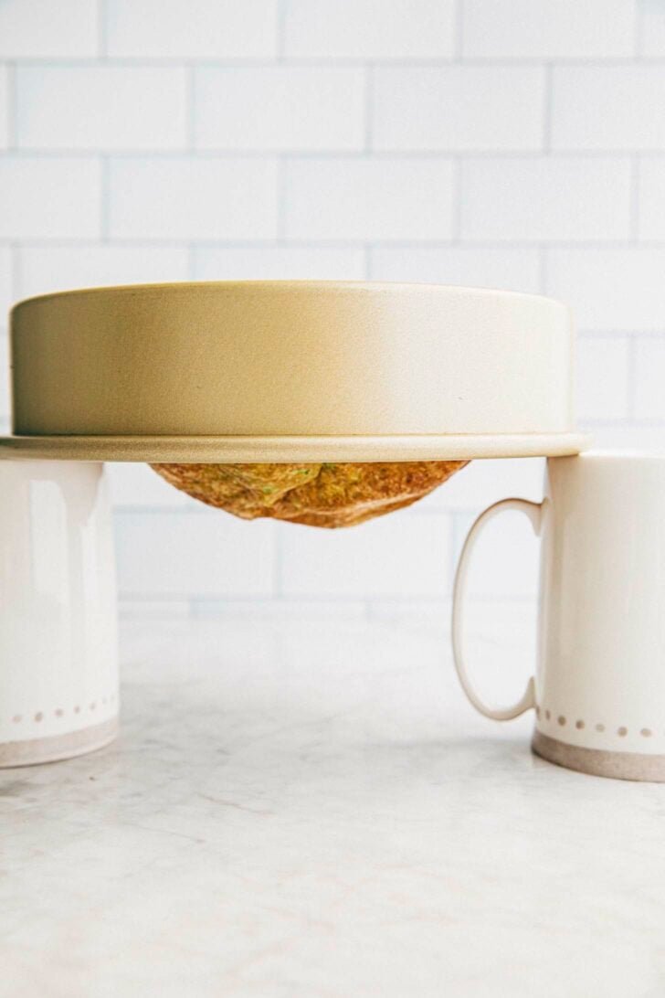 photo showing how to cool the vietnamese honeycomb cake upside down balanced on two tall mugs