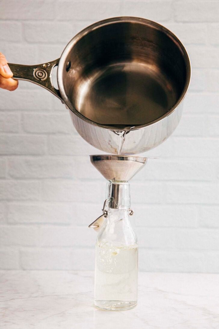 photo of michelle from hummingbird high pouring the simple syrup into a glass bottle using a metal funnel