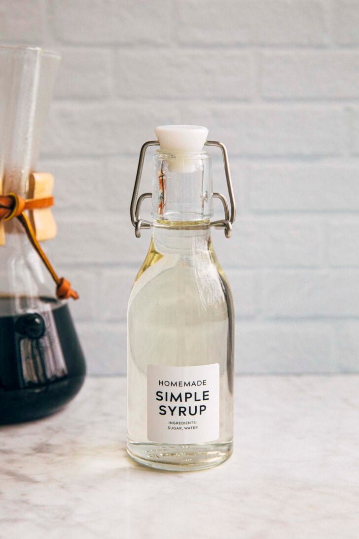 photo of a bottle of homemade simple syrup against white brick backdrop