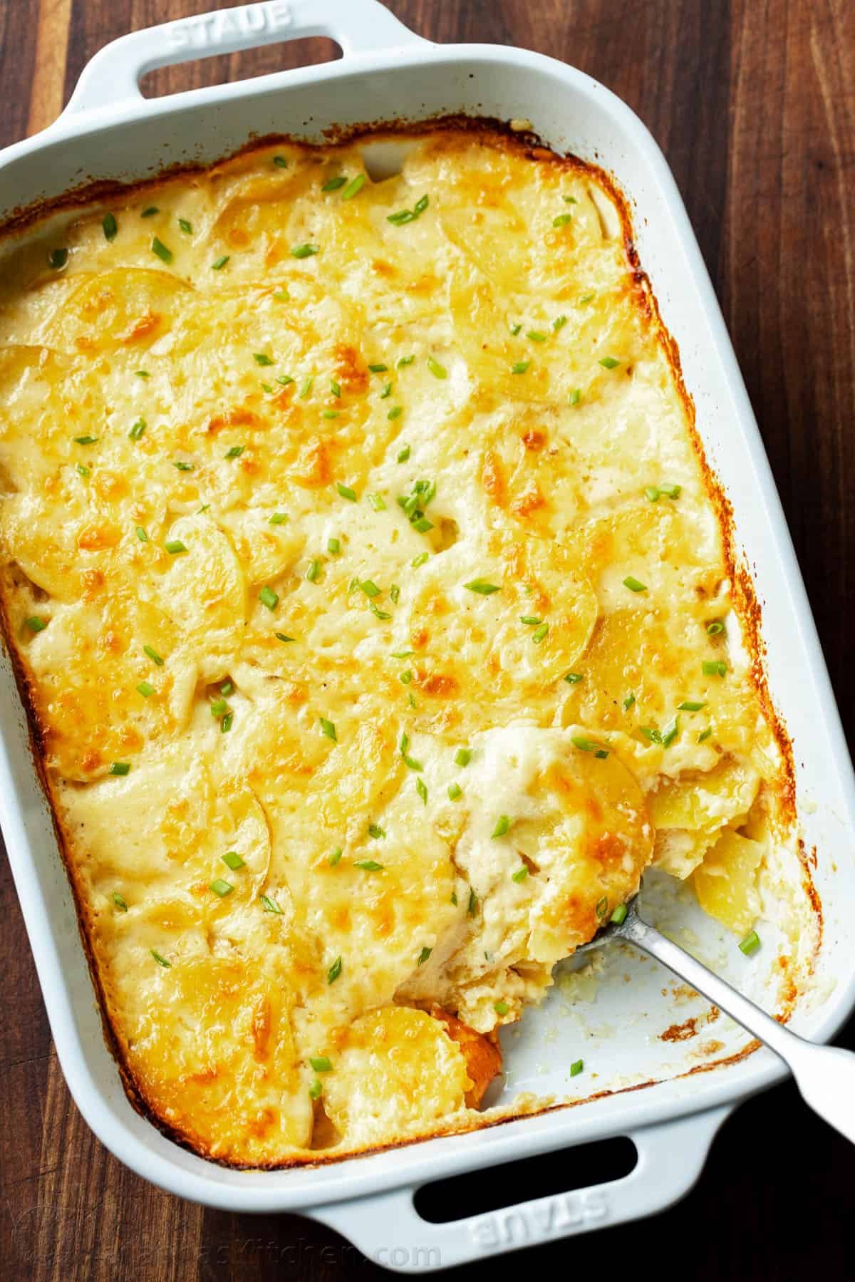 Creamy Au Gratin Potatoes are made with thinly sliced potatoes baked in a rich cheese sauce. Potato Gratin is an impressive holiday side dish. Golden baked au gratin potatoes in a rectangular baking dish with a scoop missing.
