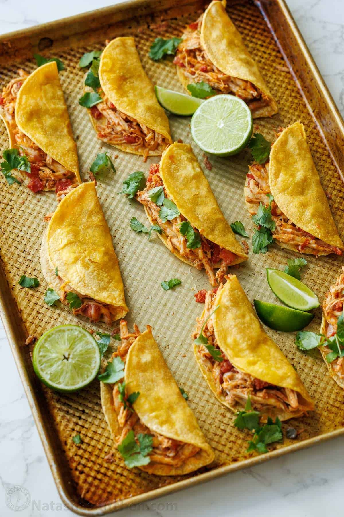 My Baked Chicken Tacos recipe is a fast and delicious 30-minute meal using rotisserie chicken and Rotel for an out-of-this world easy dinner! Baked Chicken Tacos on a cooking sheet with lime slices