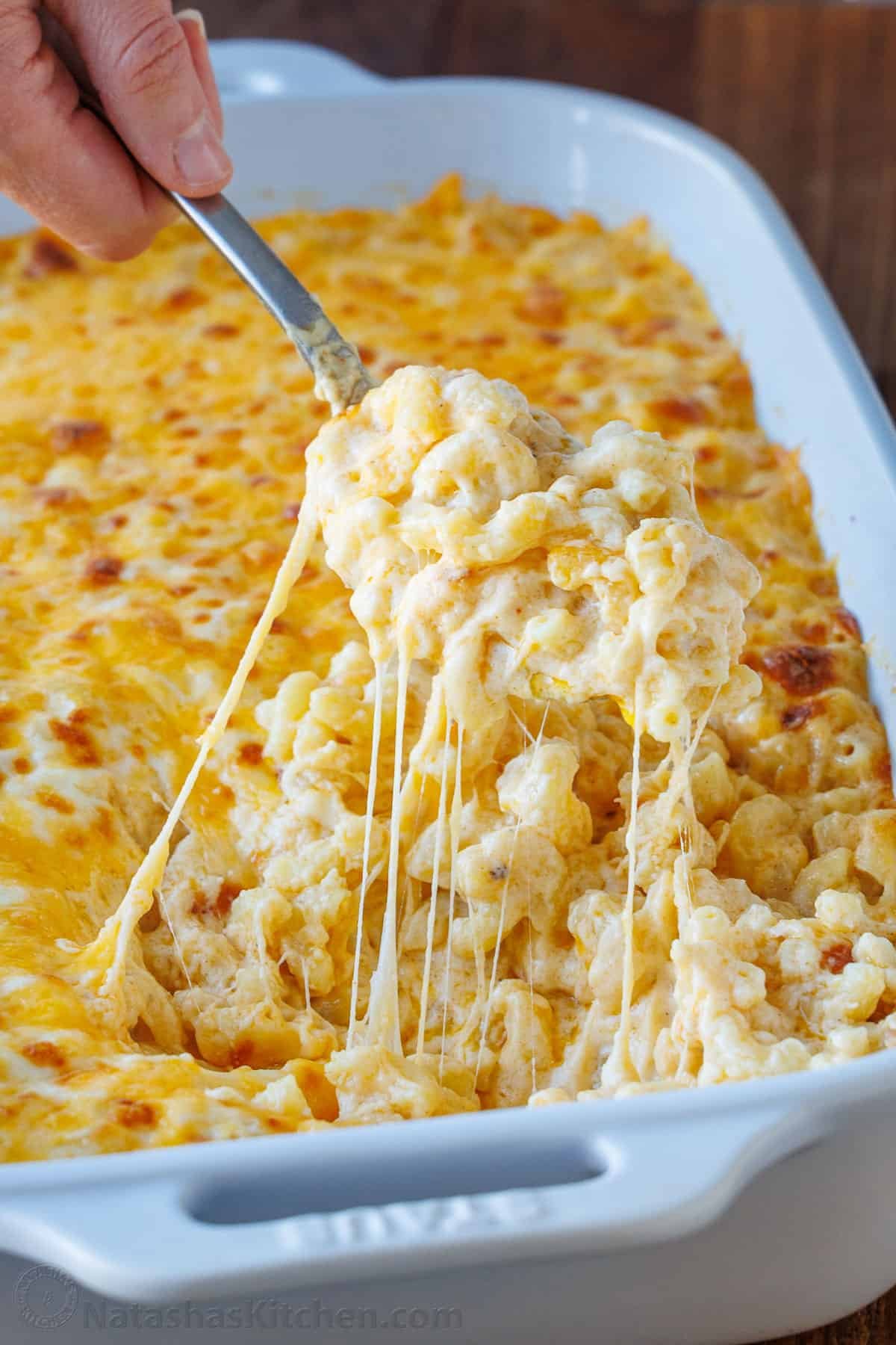My Easy homemade Baked Mac and Cheese swaps the breadcrumbs for a crowd-pleasing cheese topping. It's perfectly gooey and easy to make. Scoop of cheesy Baked Mac and Cheese removed from a white dish with a metal spoon