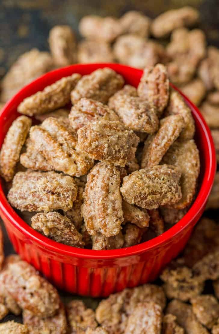 Candied pecans are easy and great for munching, gifting, and topping. The cinnamon sugar caramelizes and gives them a delicate praline crunch Candied Pecans in red bowl