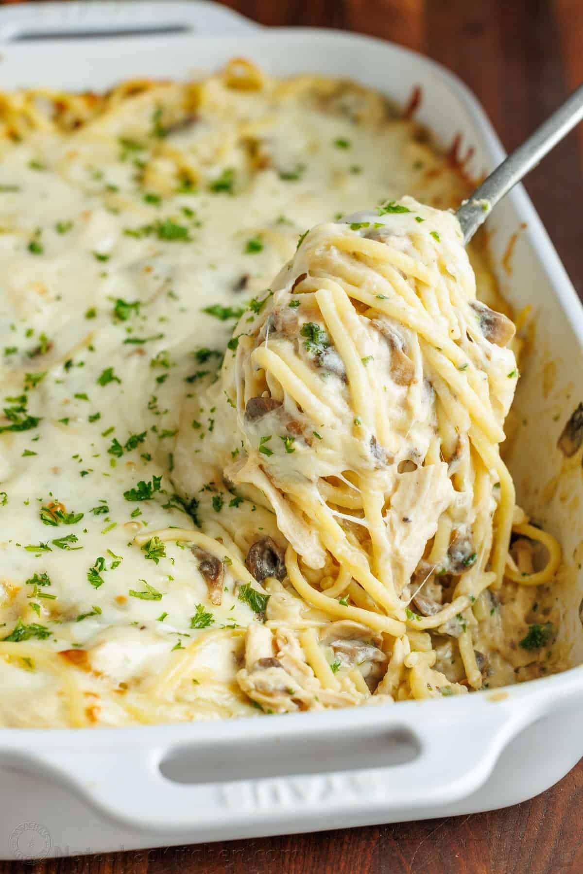 Chicken Tetrazzini is a cheesy, creamy chicken pasta bake that will have your family refilling their bowls! Make this easy casserole today! A fork scooping chicken tetrazzini recipe out of a serving dish