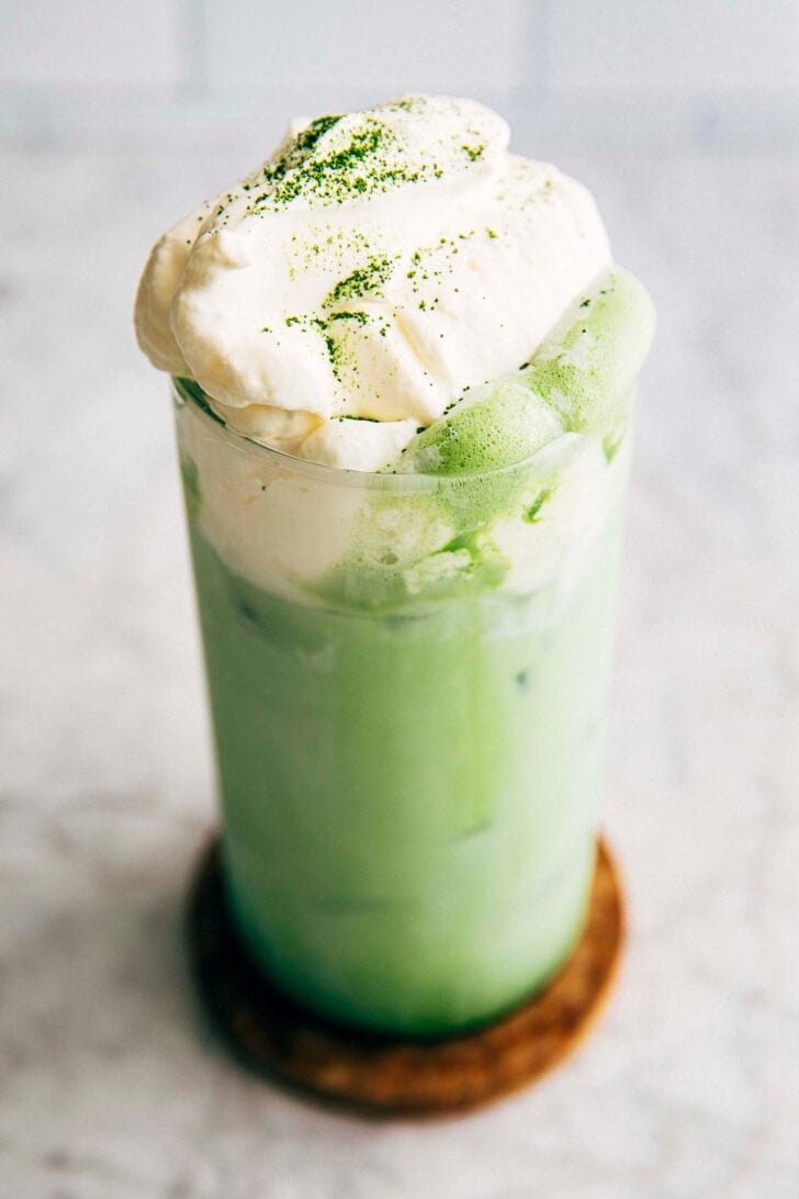 photo of matcha einspanner drink in a tall glass on a wood coaster