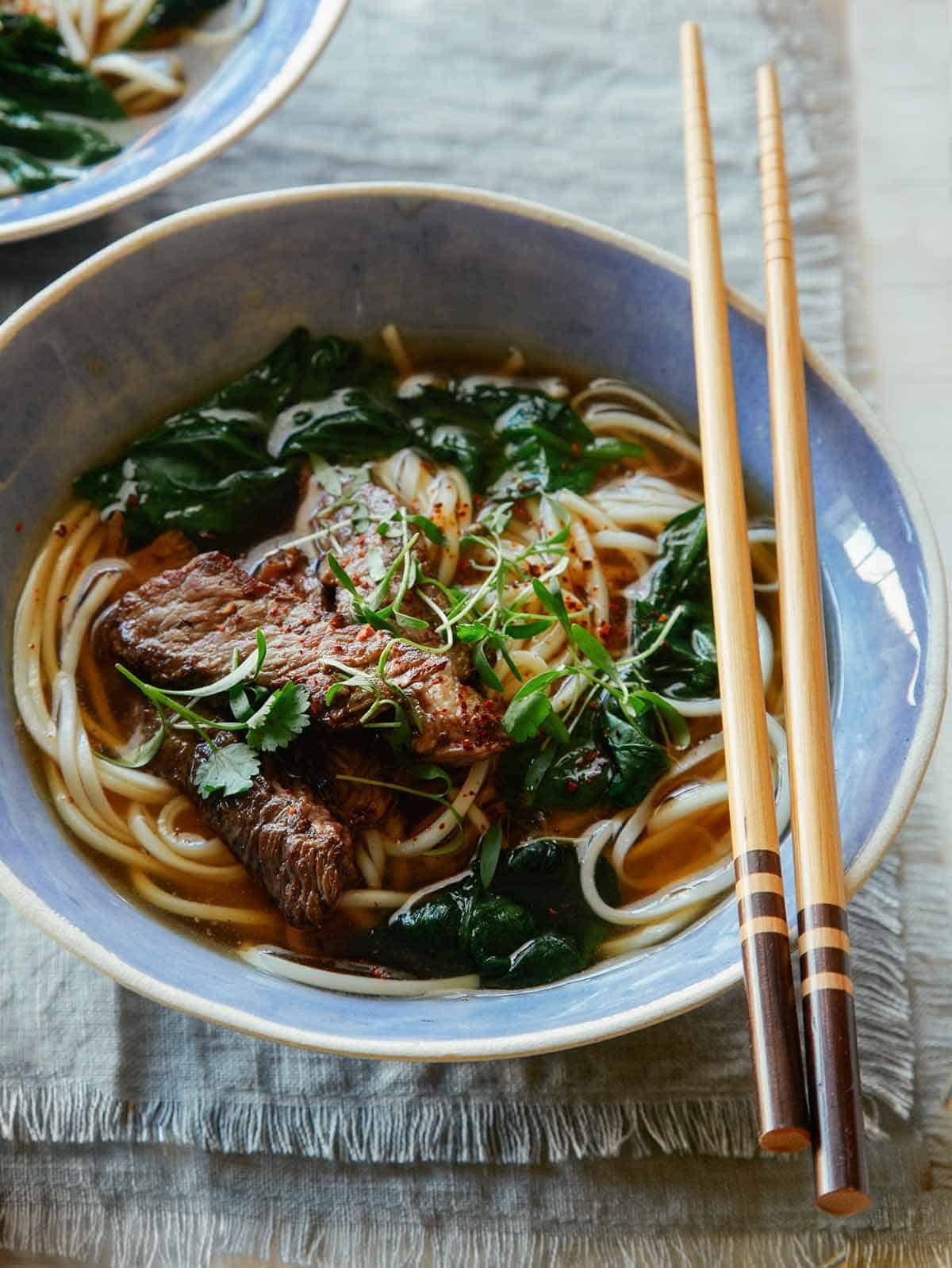 Beef noodle soup in a bowl with chopsticks.