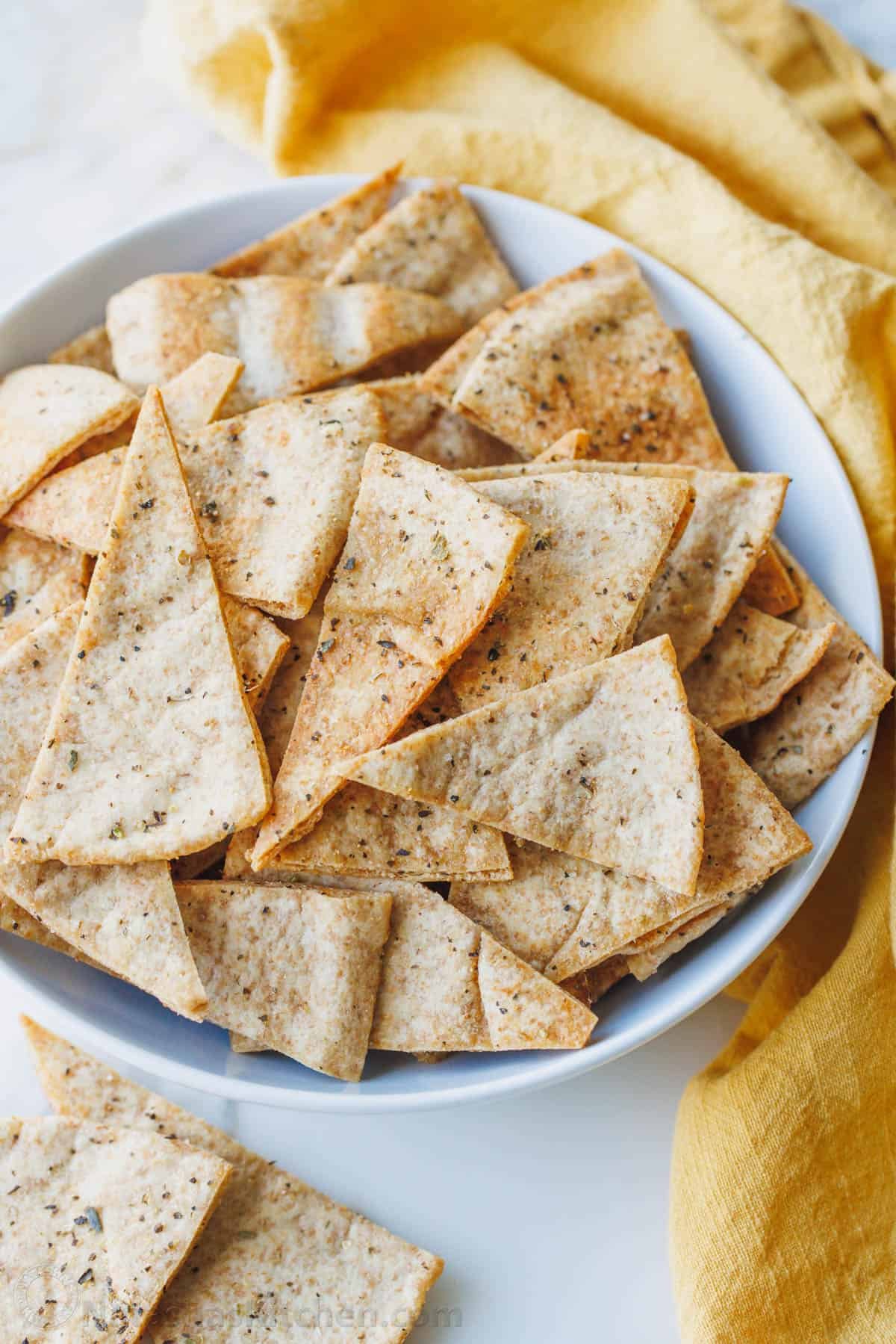 Homemade pita chips are a great way to use leftover pita bread. Crisp, crunchy, perfectly seasoned and more satisfying than store-bought. Homemade pita chips in a serving bowl
