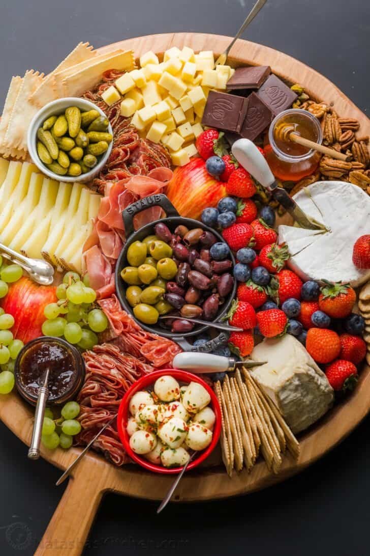 Making a Charcuterie Board is easier than you think. Sharing the best flavor pairings, and tips for arranging a meat and cheese board. Charcuterie cheese board with serving utensils