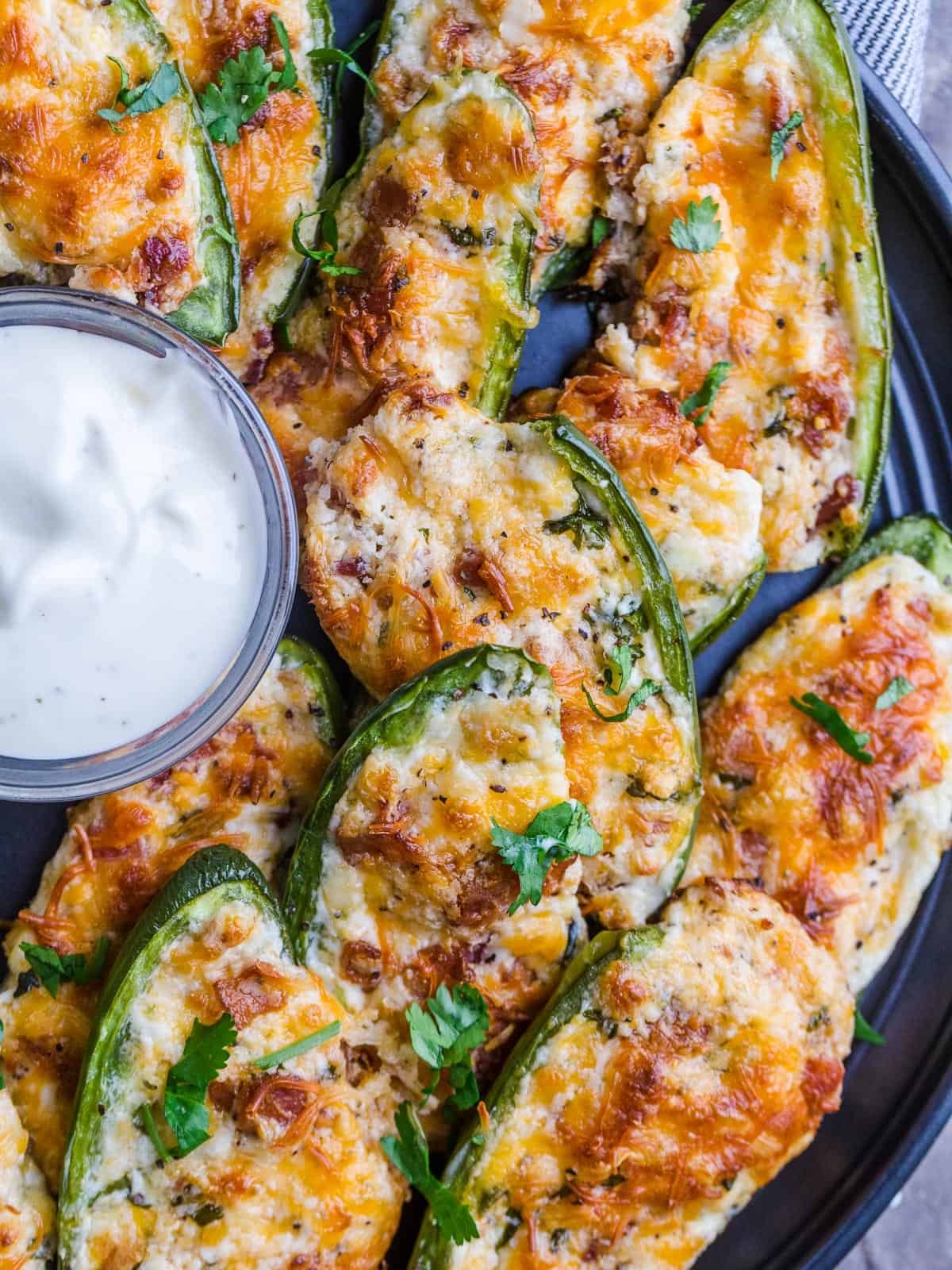 Jalapeno poppers on a platter with ranch dipping sauce in a ramekin.