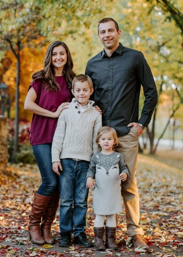 A family with fall trees in the background