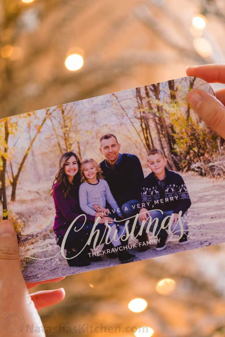 Someone holding a Christmas card that has a photo of a family.