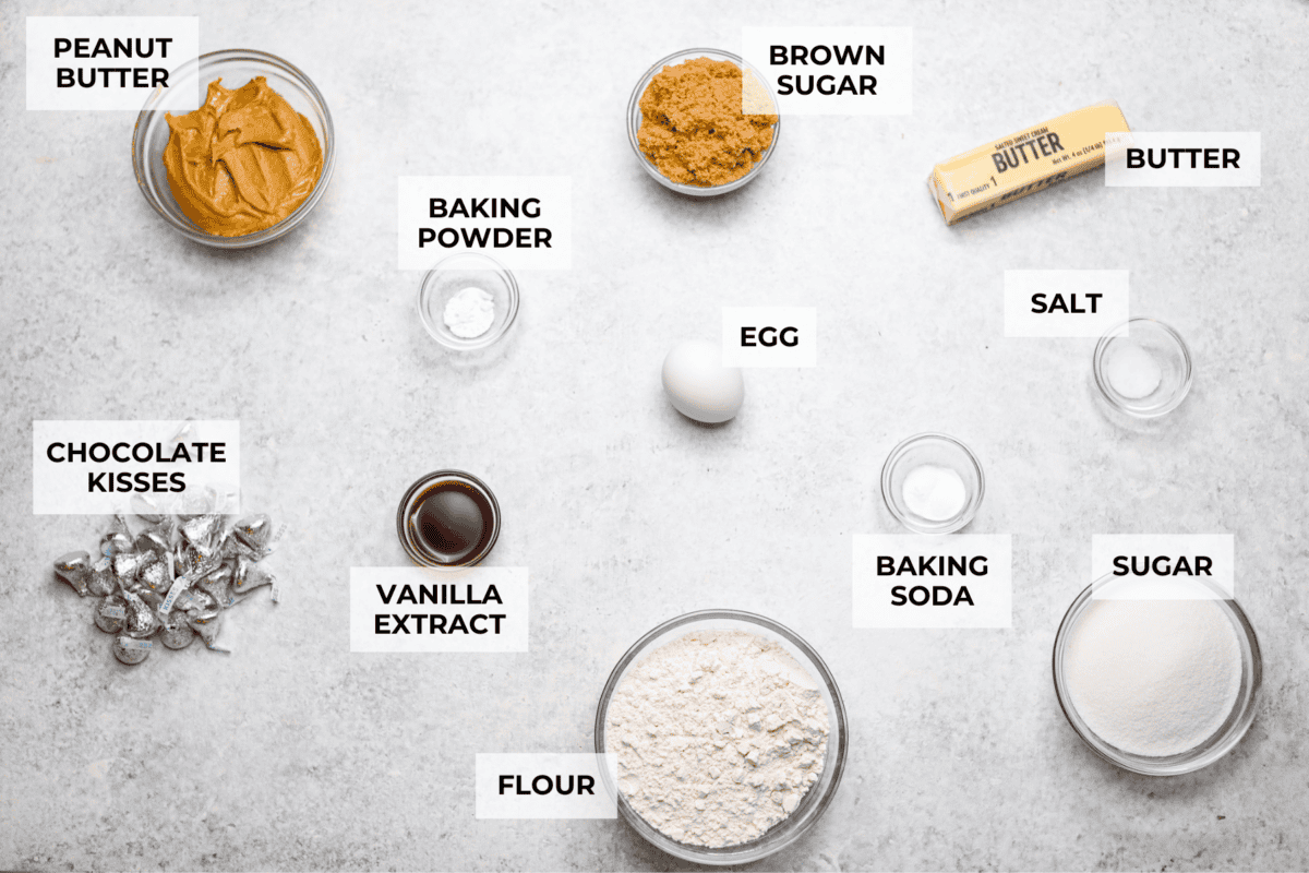 Peanut Butter Blossom Cookies are classic cookies that are perfect for every occasion. The delicious pairing of peanut butter and chocolate in these soft, buttery cookies will delight cookie lovers of all ages. Overhead shot of labeled ingredients.