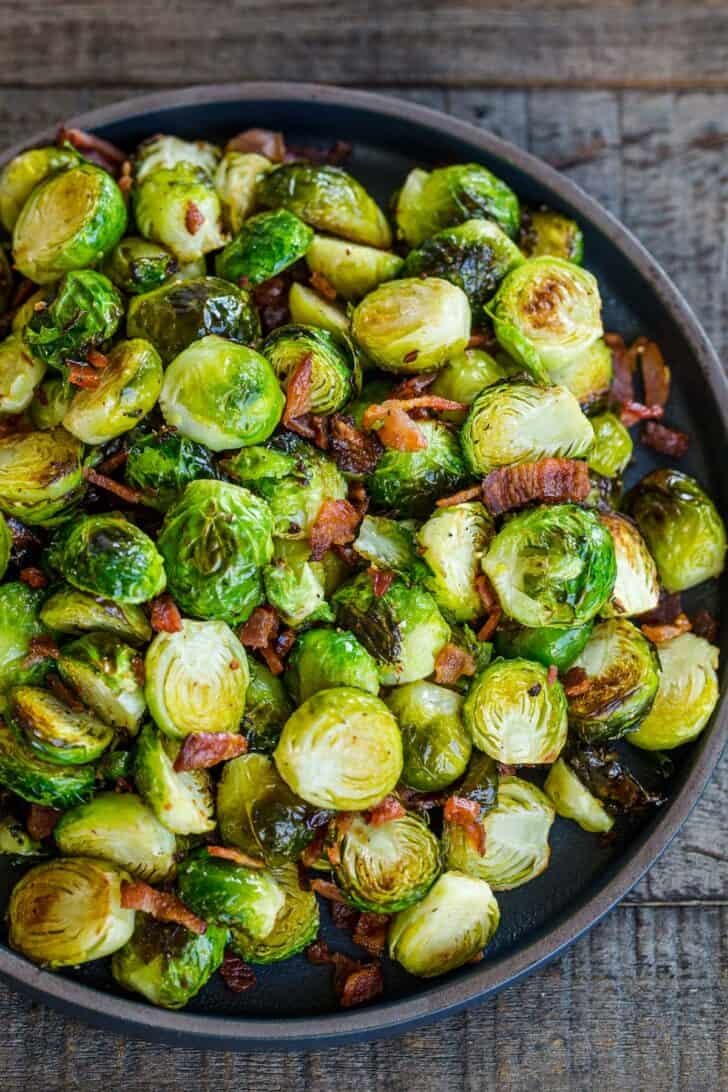 Roasted Brussels Sprouts are tender and caramelized with crisp edges. Baked Brussels sprouts are an easy, excellent side dish with just 5 ingredients. #brusselssprouts #roastedbrusselssprouts #brusselssproutsrecipe #sidedish #natashaskitchen #brusselsprouts Roasted Brussels Sprouts recipe in a bowl with bacon