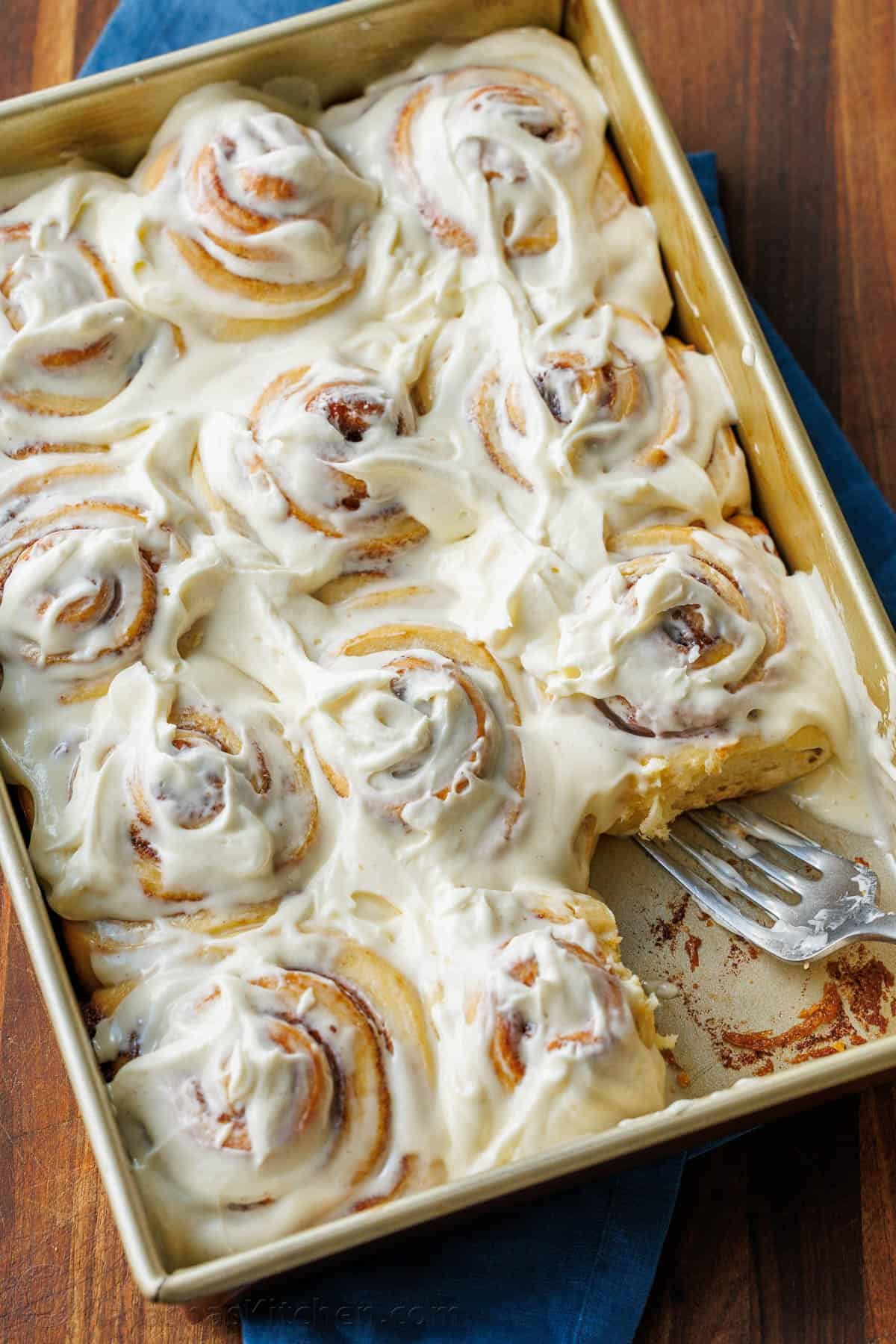 The perfect recipe for soft, fluffy, and buttery Sourdough Cinnamon Rolls, layered with cinnamon sugar and topped with creamy cream cheese frosting. Sourdough cinnamon rolls frosted in a baking pan with 1 cinnamon roll removed