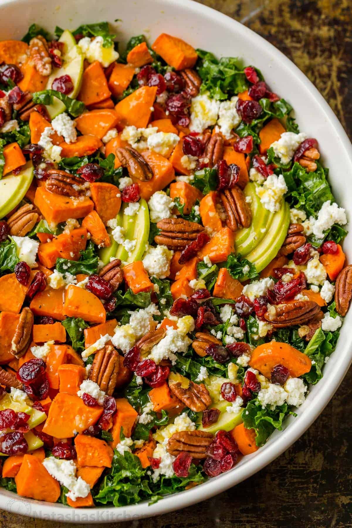 Roasted Sweet Potato Salad has all the best Fall flavors. Loaded with kale, sweet potato, apple, pecans, goat cheese, and the best dressing. Roasted sweet potato salad with kale in a large salad bowl