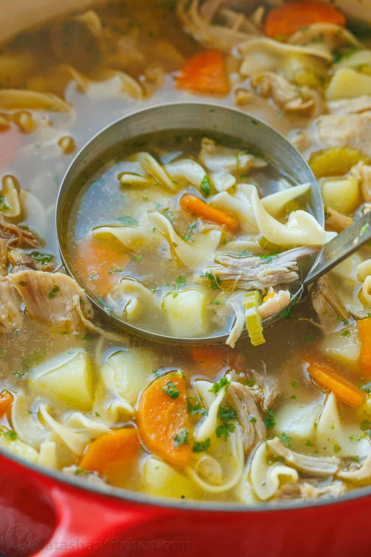 This hearty Turkey Noodle Soup recipe is warm, comforting, and simple to make. It's the perfect way to use the leftover turkey from your holiday dinners. Hearty turkey noodle soup being scooped out of a pot with a large ladle